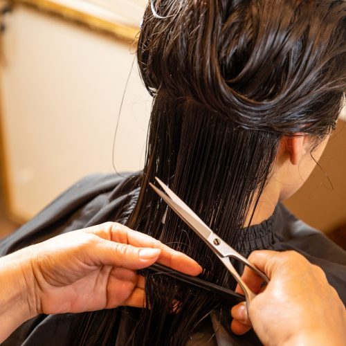 a woman cutting another woman's hair with scissors